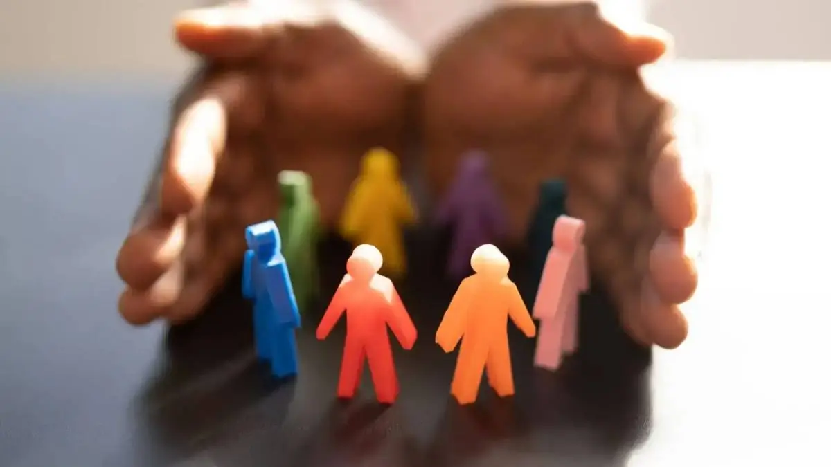 Mains protectrices entourant des figurines colorées, pour illustrer l’accessibilité et l’accompagnement de tous les profils au cabinet Basile Debec.