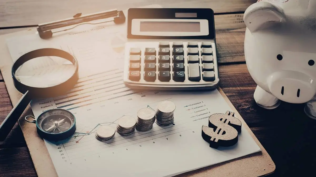 Calculatrice, graphiques financiers et tirelire illustrant le budget investissement avec le Cabinet Basile Debec.