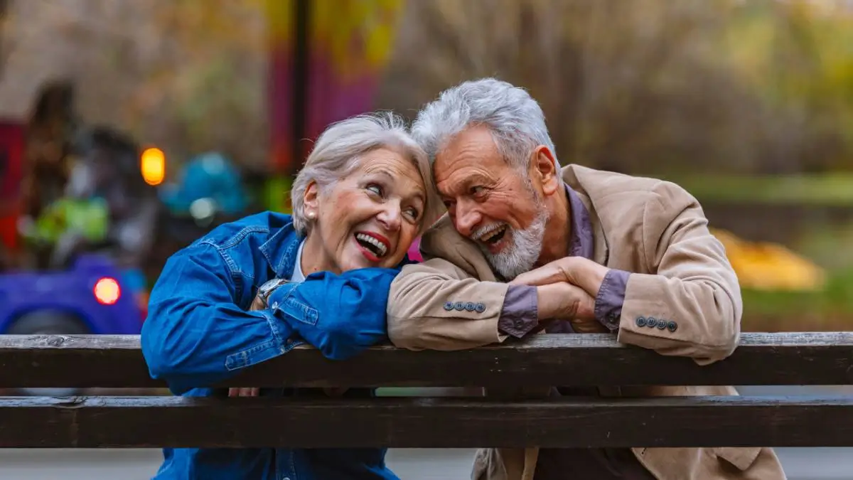 Couple de seniors souriant sur un banc, illustrant l’importance de bien préparer sa retraite pour profiter sereinement de cette nouvelle étape de vie.